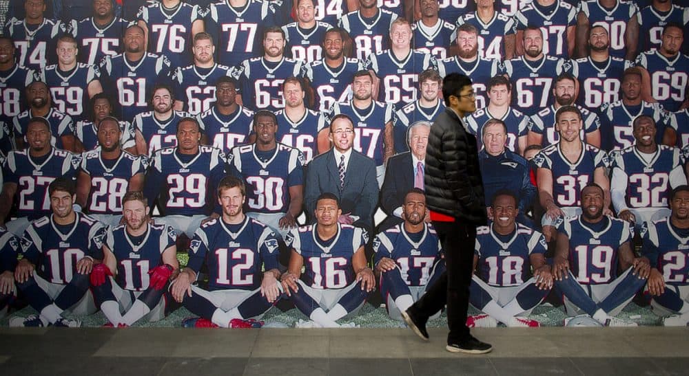 In this photo, a man walks past a life-sized team photo of the New England Patriots at a National Football League publicity event held in Beijing, Sunday, Nov. 8, 2015. The NFL has been aggressively promoting football in China hoping to take advantage of rising income and growing taste for exotic foreign sports. (Mark Schiefelbein/ AP)