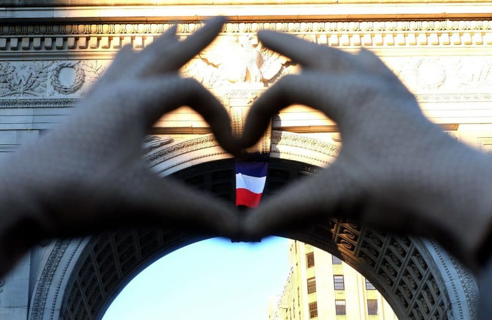 A woman makes a heart sign with her fingers framing a French national flag placed on the arch at the Washington Square Park during a vigil to show solidarity with the citizens of France on November 14, 2015 in New York, a day after the Paris terrorist attacks. Islamic State jihadists claimed a series of coordinated attacks by gunmen and suicide bombers in Paris on November 13 that killed at least 129 people in scenes of carnage at a concert hall, restaurants and the national stadium. (Jewel Samad/AFP/Getty Images)