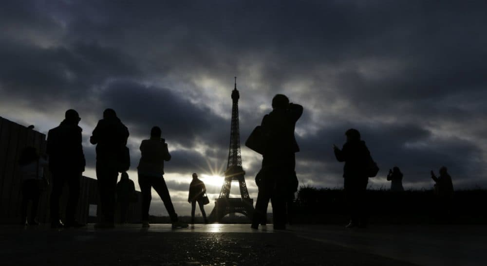 Julie Wittes Schlack: As the people of Paris and other terrorized cities resume normal life, we should consider whether our routines and distractions help us cope or help us adapt to the unacceptable. In this Sunday, Nov. 15, 2015 photo, tourists visit the Eiffel Tower in Paris, France. (Amr Nabil/ AP)