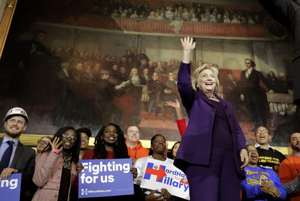 Democratic presidential candidate Hillary Clinton, right, stands on stage as she greets people at the start of a rally at Faneuil Hall. (Steven Senne/AP)