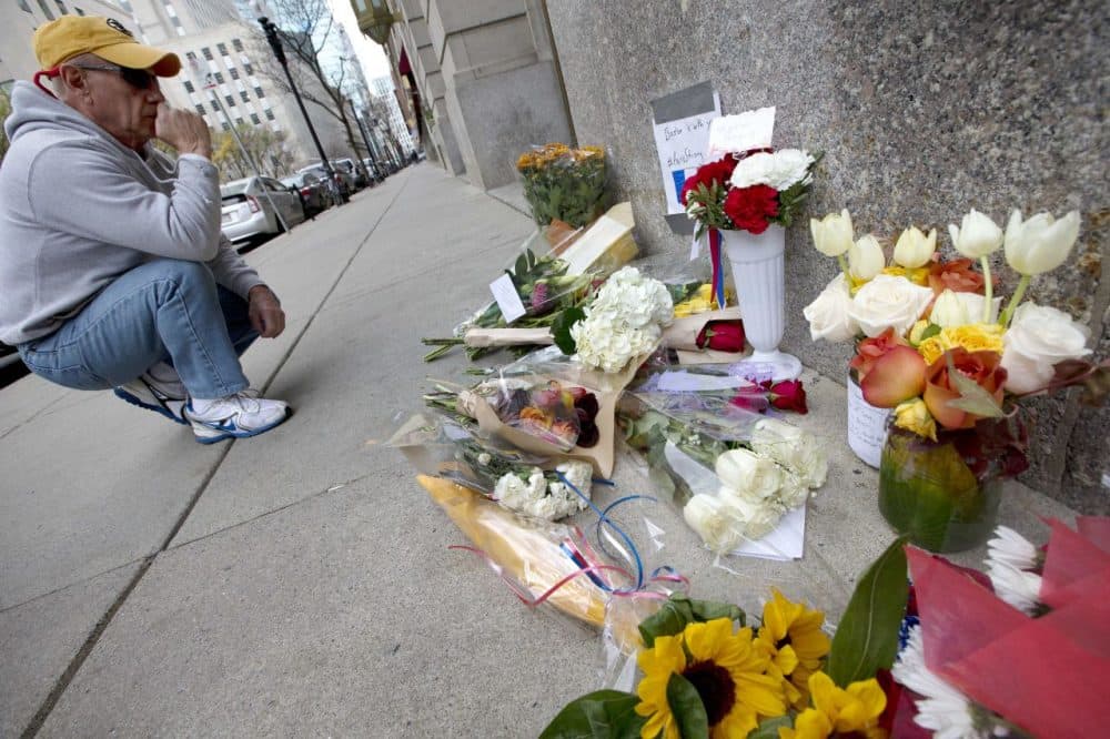 An unidentified man pauses after placing flowers on a make-shift memorial outside the French Consulate in Boston on Saturday. (Michael Dwyer/AP)