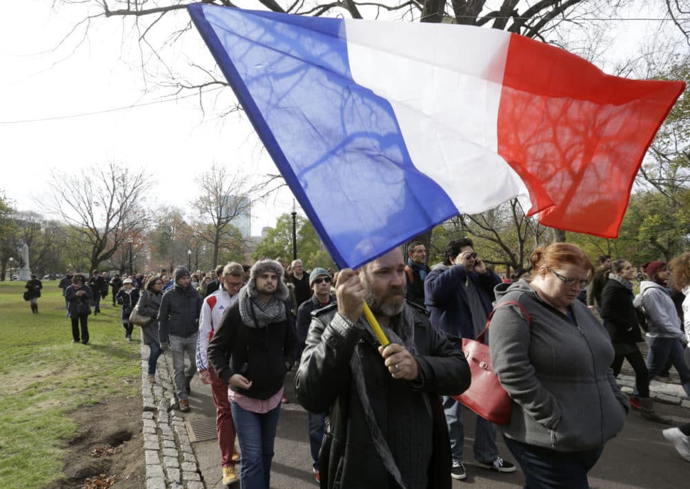 Austin Wolfe, of Quincy, Mass., who holds both U.S. and French citizenship, carries a French flag at a vigil Sunday in Boston, held in sympathy for the people of Paris. (Steven Senne/AP)