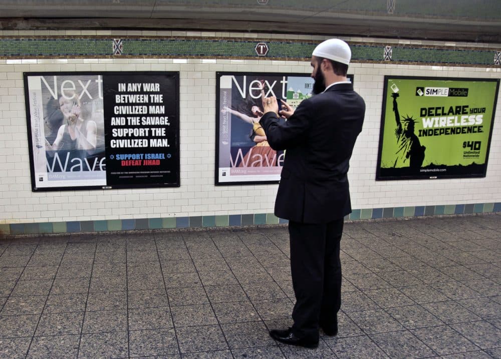 The MBTA banned ads on the T about political, social, or religious issues on Monday. Pictured here is Cyrus McGoldrick, Advocacy Director for Council on American-Islamic Relations, taking a photo of an anti-Muslim that, in 2012, sparked a similar controversy in New York, leading the MTA to ban all political and religious ads. (AP Photo/Bebeto Matthews)