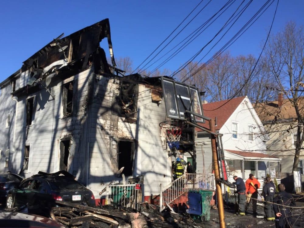 Officials examine a Lynn building where a fire killed four people. (Curt Nickisch/WBUR)