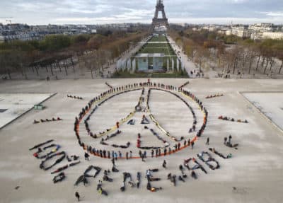 Environmentalist activists form a human chain representing the peace sign and the spelling out &quot;100% renewable,&quot; on the side line of the COP21, United Nations Climate Change Conference near the Eiffel Tower in Paris on Sunday. (Michel Euler/AP)