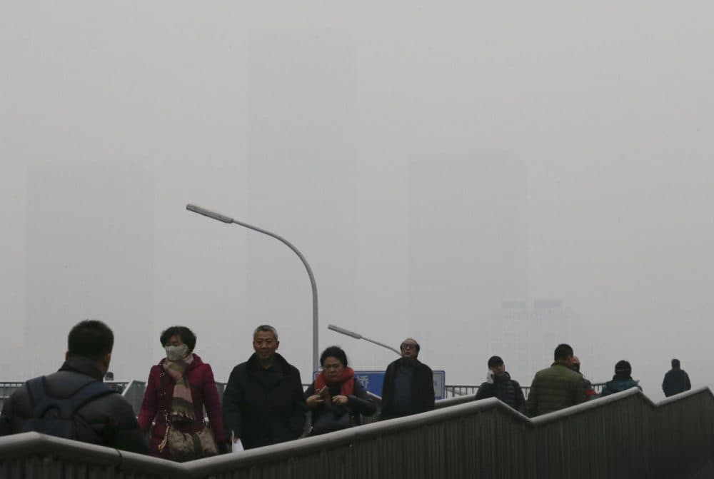 People walk on a pedestrian overhead bridge as office buildings in Central Business District of Beijing are shrouded with heavy haze, Tuesday, Dec. 8, 2015. Beijing's red alerts for smog are as much about duration as they are about severity of pollution forecasts. The forecasting model must predict three or more days of smog with levels of 300 or higher on the city's air quality index - which typically would include having levels of dangerous PM 2.5 particles of about 10 times the safe level. (Andy Wong/AP Photo)