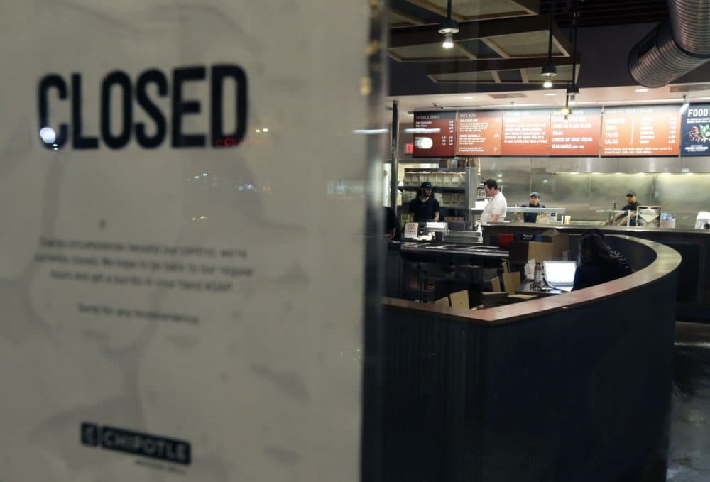 People stand inside a closed Chipotle restaurant on Monday in the Cleveland Circle neighborhood of Boston. (Steven Senne/AP)