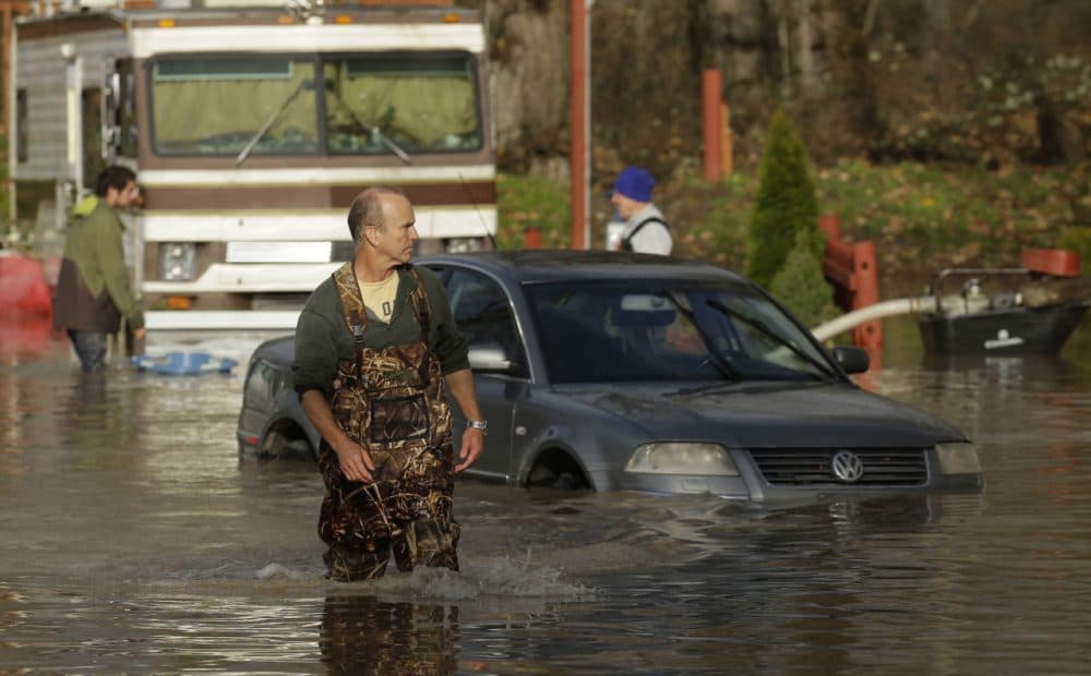 Kevin McLeod, co-owner of the Riverview RV Park, wades through floodwaters near a partially submerged car Wednesday, Dec. 9, 2015, after he hooked up a pump to get rid of water that flooded RV's and other vehicles Wednesday morning in Puyallup, Wash. The National Weather Service says wind and rain are expected to slow Wednesday, but snow may continue to fall in the mountains. (Ted S. Warren/AP)