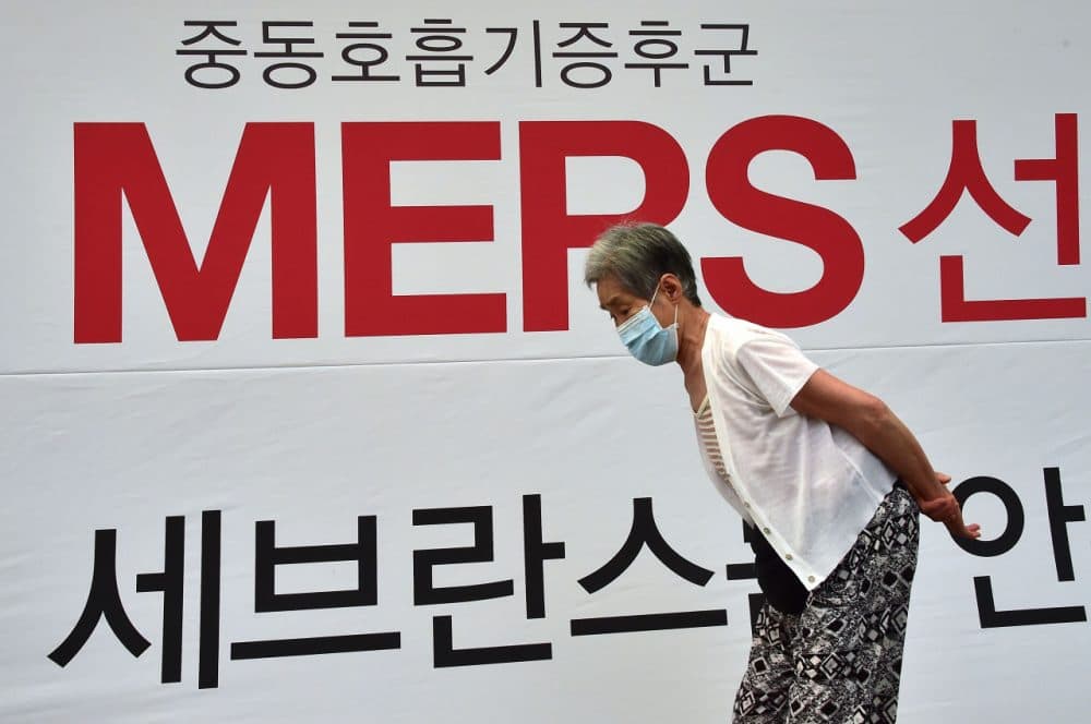 An elderly woman wearing a face mask walks past signage on MERS at Severance Hospital in Seoul on June 16, 2015. South Korea on June 16 reported three more fatalities from the MERS outbreak but health authorities said they were cautiously optimistic the worst was over as the number of new cases was falling. (Jung Yeon-Je/AFP/Getty Images)