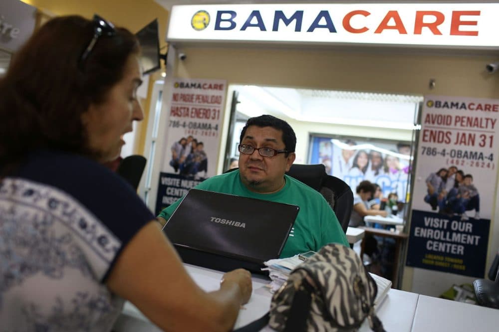 Martha Lucia (left) sits with Rudy Figueroa, an insurance agent from Sunshine Life and Health Advisors, as she picks an insurance plan available in the third year of the Affordable Care Act at a setup in the Mall of the Americas in Miami. (Joe Raedle/Getty Images)