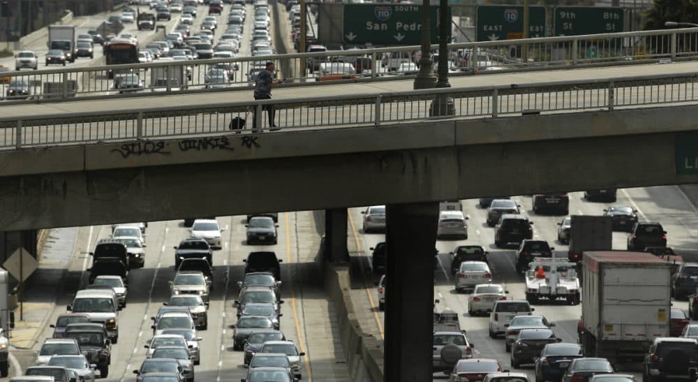 Earlier this month, in a rare showing of bipartisan compromise, Congress passed a $305 billion measure to fund roads, bridges and rail lines. In this May 6, 2015 photo, a man walks on the Wilshire Boulevard overpass as traffic slowly moves along the 110 Freeway in downtown Los Angeles. (Jae C. Hong/ AP)
