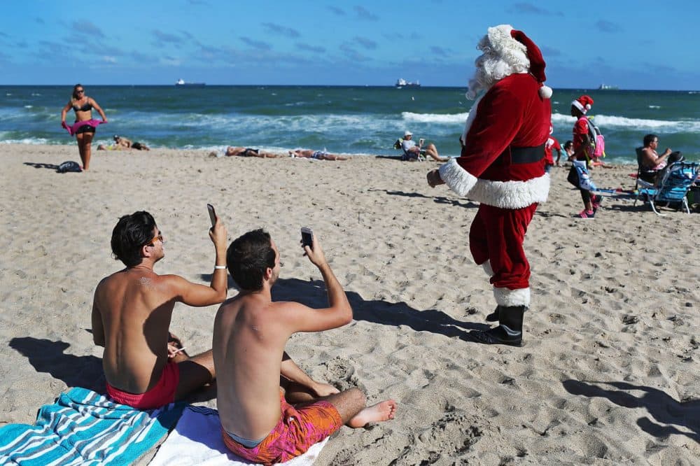 Timmy McGovern (dressed as Santa Claus) walks along the beach passing out candy canes and posing for pictures with beach goers on December 21 in Fort Lauderdale, Florida. Santa Claus has been visiting the beach just before Christmas for over 30 years.  (Joe Raedle/Getty Images)