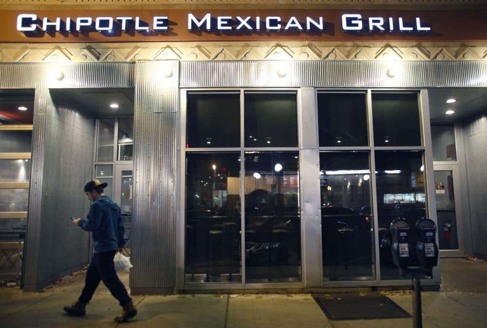 A man walks near a closed Chipotle restaurant on Monday, in the Cleveland Circle neighborhood of Boston. (Steven Senne/AP)