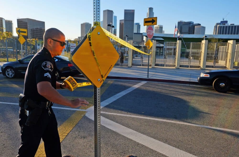 A police officer puts up yellow tape to close the school outside of Edward Roybal High School in Los Angeles, on Tuesday morning after a threat. (Richard Vogel/AP)