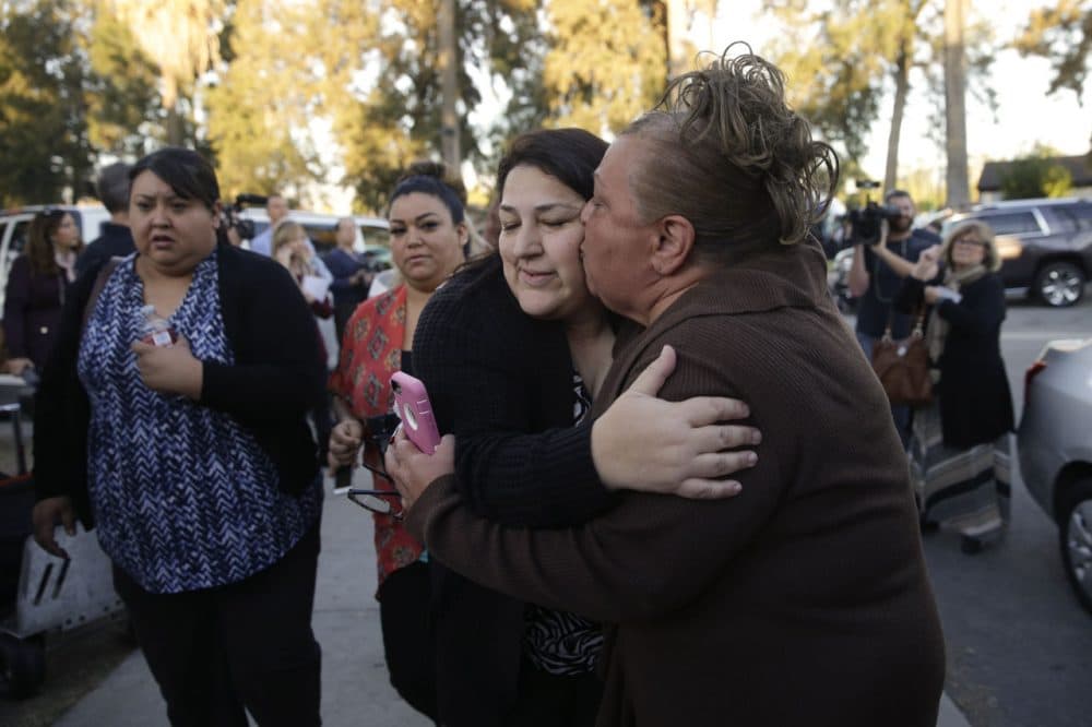 A woman kissed her sister, a survivor of a shooting rampage that killed at least 14 people and wounded more than a dozen others, as they reunited at a community center in San Bernardino Wednesday. (Jae C. Hong/AP)