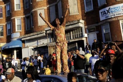 A woman stands on a car during a party in the street in Baltimore on Saturday, May 2, 2015, the day after charges were announced against the police officers involved in Freddie Gray's death. (AP Photo/David Goldman)