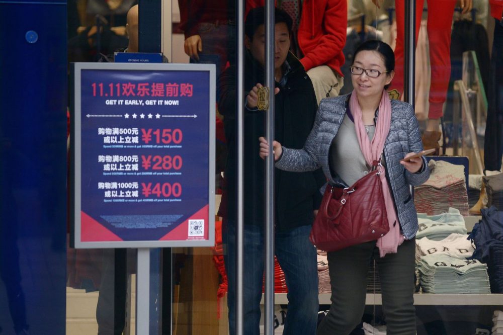 A woman walks out a shop past a &quot;Singles Day&quot; sales promotional board in Beijing on November 11, 2015.  (Wang Zhao/AFP/Getty Images)