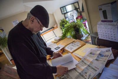 Ronjon Cameron, seen here in late December in his Pittsfield home, pores over DNA and legal documents, as well as old newspapers he has collected, as research for a book he is writing. (Jesse Costa/WBUR)