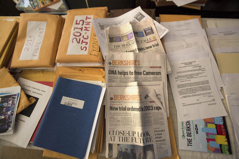 Ronjon Cameron is now free, after the state high court overturned his conviction and prosecutors decided to drop the case. In his Pittsfield home, Cameron's table is full of documents and old newspapers he has collected as research for a book he is writing. (Jesse Costa/WBUR)