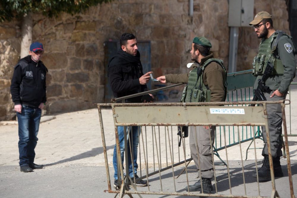 A Palestinian man has his identity checked by Israeli border police patrolling the streets of the West Bank city of Hebron on January 5, 2016. (Menahem Kahana/AFP/Getty Images)