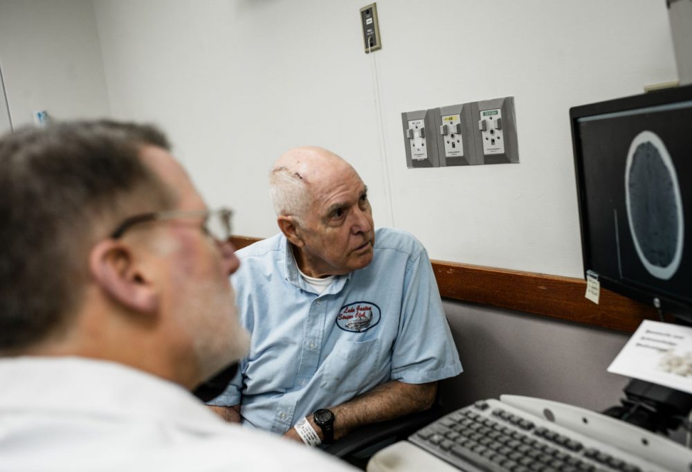 Tom Feild looks at a brain scan with his doctor at Virginia Commonwealth University Medical Center in Richmond, Va. Feild had brain surgery after experiencing a low-grade headache that wouldn't go away and difficulty driving. (Matailong Du for NPR)