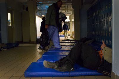 Men prepare to sleep on 25-inch-wide mats in the lobby of Boston's Pine Street Inn. (Hadley Green for WBUR)