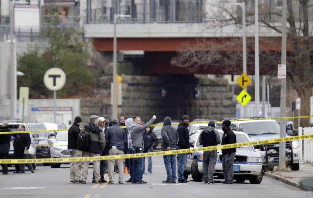 Law enforcement officers gather near the scene where a Boston police officer was shot Friday morning in Dorchester. Police say the officer, who was shot in the leg after pulling over a known drug dealer, is expected to survive. (Stephan Savoia/AP)
