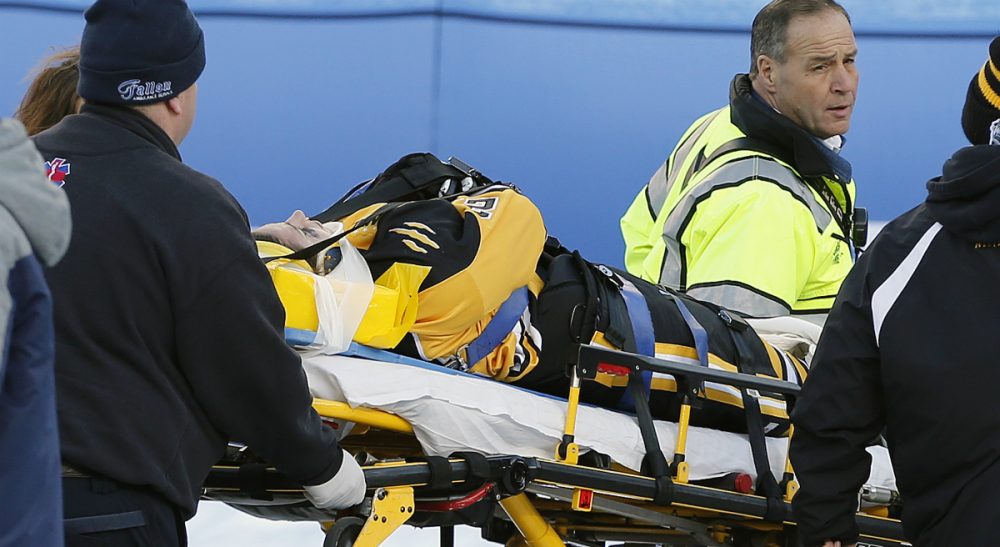Full face shields protect ice hockey players from dental and facial injuries, but they might also increase the risk of devastating spinal cord injuries. In this photo, Boston Pride's Denna Laing is wheeled off the ice after being injured during a women's hockey game against the Montreal Les Canadiennes at Gillette Stadium in Foxborough, Mass., Thursday, Dec. 31, 2015. (Michael Dwyer/ AP)