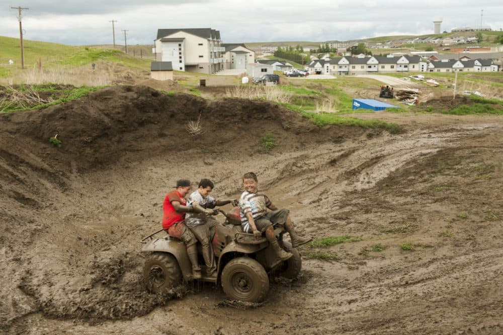 Children ride an ATV through a muddy construction area at the edge of a housing development  in Watford City, North Dakota, one of many built during the oil boom. (Andrew Cullen)