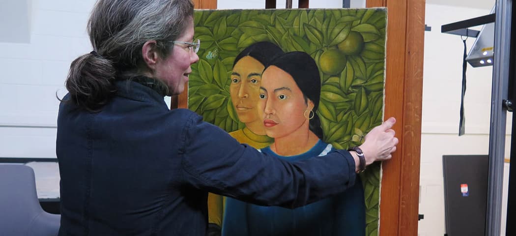 MFA Conservator of Paintings Rhona MacBeth places Frida Kahlo's “Dos Mujeres (Salvadora y Herminia) (1928)” on an easel for display. It was the first painting Kahlo ever sold. (Andrea Shea/WBUR)