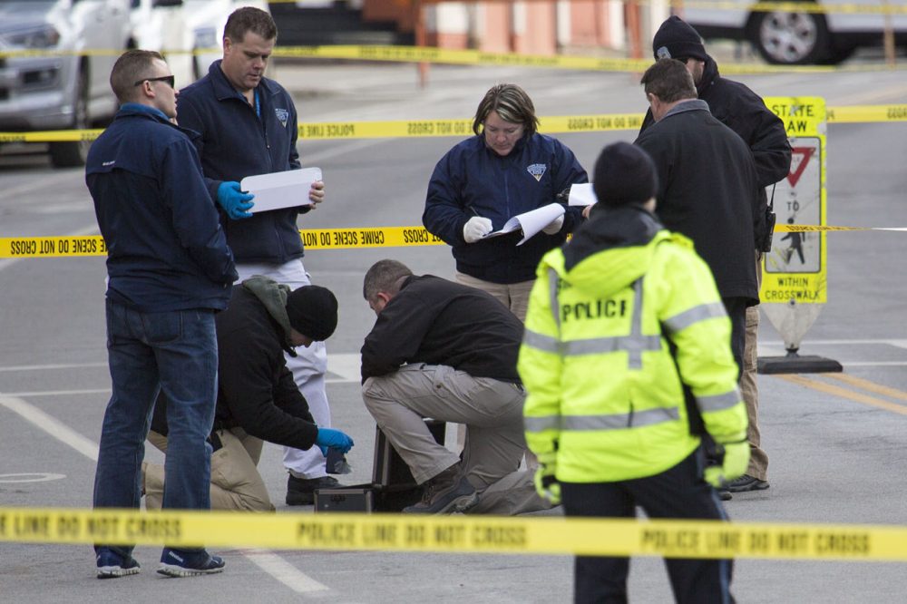 A crime lab technician dusts for prints from a phone as Brookline police examine the crime scene. (Jesse Costa/WBUR)