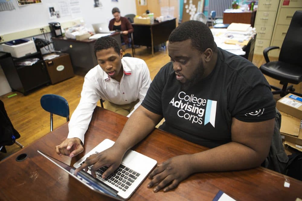 College Advising Corps aims to increase the number of low-income students who apply to college. The nonprofit currently has advisers in 24 Boston high schools. Pictured here, senior Josue Jean-Pierre, left,  and Rudy Luders, with College Advising Corps, review college application information at the Green Academy in Brighton. (Jesse Costa/WBUR)
