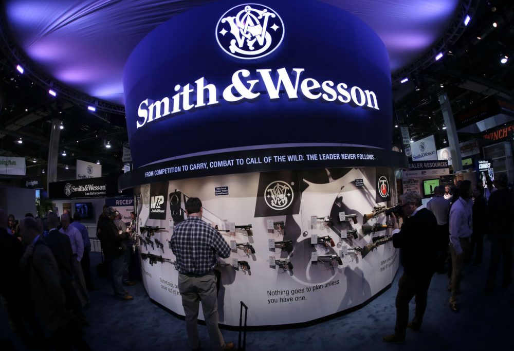 In this 2014 file photo, Las Vegas trade show attendees examine handguns and rifles in the Smith &amp; Wesson display booth. The Springfield firearms maker's shares jumped Monday. (Julie Jacobson/AP)
