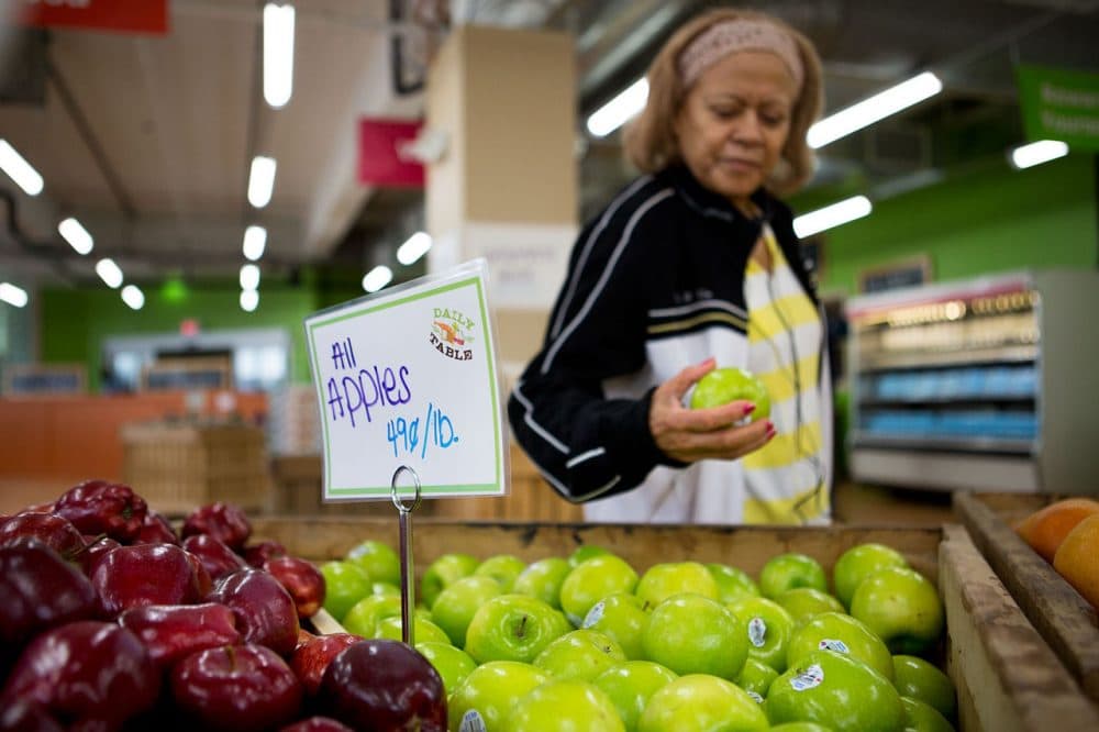 Noemi Sosa looks at an apple as she shops at the Daily Table, the first not-for-profit supermarket located in Dorchester. Dorchester Community Food Co-op would bring much-needed fresh food to the Four Corners neighborhood of Dorchester. (Jesse Costa/WBUR)