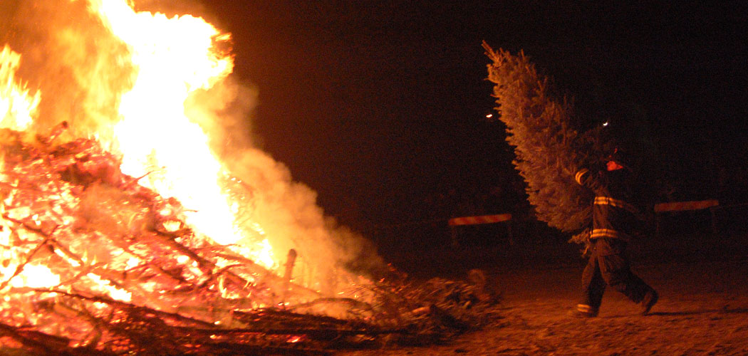 A firefighter throws a tree onto Salem's Christmas tree bonfire. (Greg Cook)