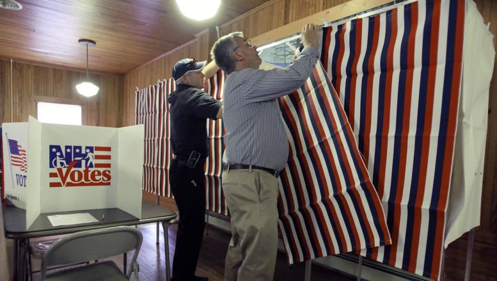 This year's presidential primary is the first in which New Hampshire's voters will be required to show identification before they can cast their ballots. Pictured here, Calab Pike, left, and Jack Parsons set up voting booths in Tuftonboro, New Hampshire, in 2014. (Jim Cole/AP)