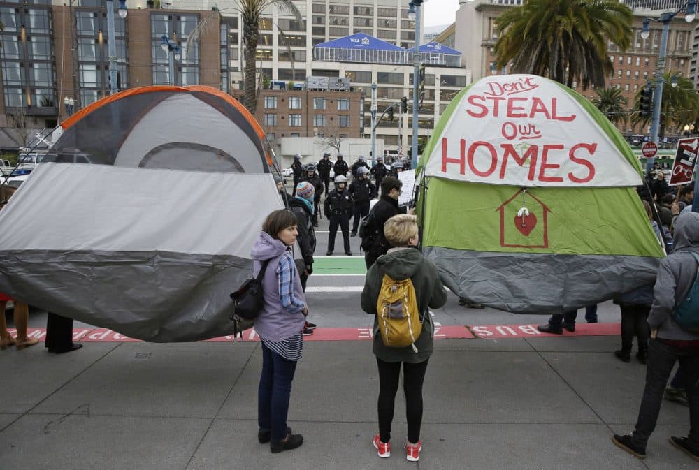 Demonstrators hold up tents during a protest to demand city officials do more to help homeless people outside Super Bowl City, a pro-football's weeklong theme park near the famed Ferry Building in San Francisco on Wednesday, Feb. 3, 2016. Dozens protested what they say is San Francisco Mayor Ed Lee's plan to push homeless people out of the scenic bay-front Embarcadero, where Super Bowl festivities are being held. (Eric Risberg/AP)