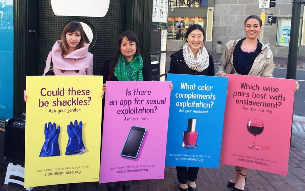 Public policy fellows with San Francisco's Department on the Status of Women hold mockups of anti-trafficking billboards. (Tara Siler/KQED)
