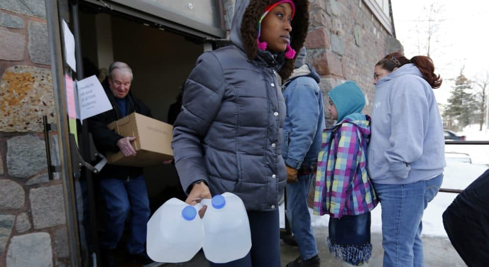 In this Tuesday, Feb. 3, 2015 photo, a Flint resident carries free water being distributed at the Lincoln Park United Methodist Church in Flint, Mich. Since the financially struggling city broke away from the Detroit water system in April 2014, residents have been unhappy with the smell, taste and appearance of water from the city's river as they await the completion of a pipe to Lake Huron. They also have raised health concerns, reporting rashes, hair loss and other problems. (Paul Sancya/AP)
