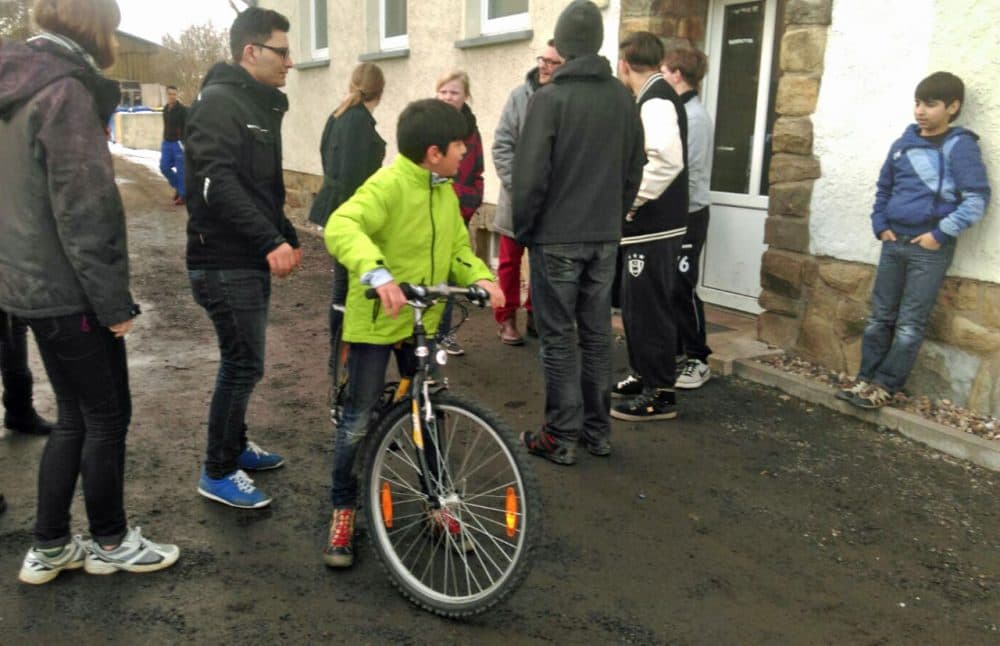 Ramzi, 13, from Lebanon tries out his new bicycle as volunteers and other newly arrived residents in Clausnitz look on. (Marc Lalonde)