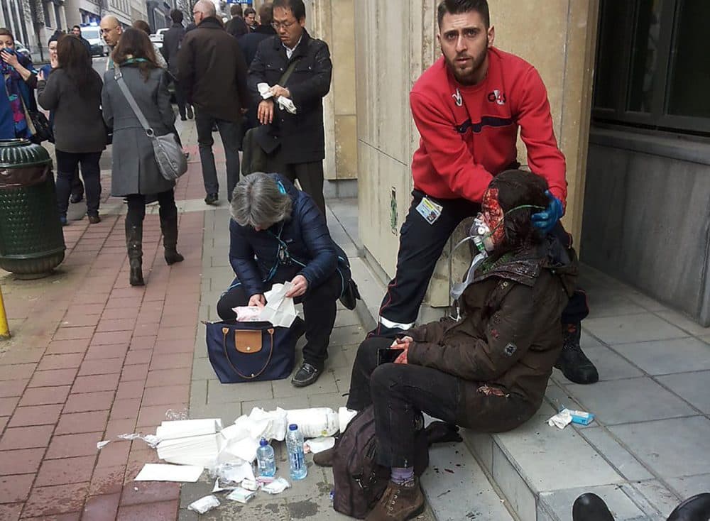 A private security guard helps a wounded women outside the Maalbeek metro station in Brussels on March 21, 2016 after a blast at this station located near the E.U. institutions.
Belgian firefighters said at least 26 people had died after &quot;enormous&quot; blasts rocked Brussels airport and a city metro station today, as Belgium raised its terror threat to the maximum level. (Michael Villa/AFP/Getty Images)
