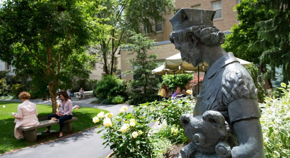A statue of a nurse holding a bear near the entrance to Prouty Garden from Boston Children’s Hospital’s main building. More than 15,000 people have signed a petition to save the garden from demolition. (Robin Lubbock/WBUR)
