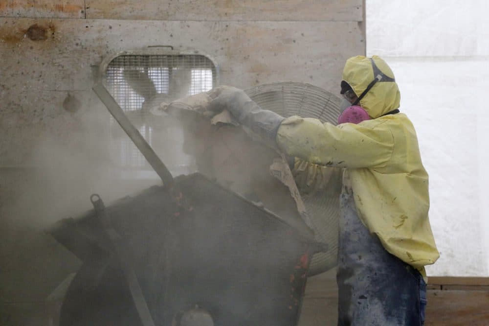 A worker wearing a respirator mask pours a bag of concrete mix into a hopper at the 3 World Trade Center construction site, Monday, April 14, 2014 in New York. Three World Trade Center, now up to seven floors, will be 80 stories when completed. (Mark Lennihan/AP)