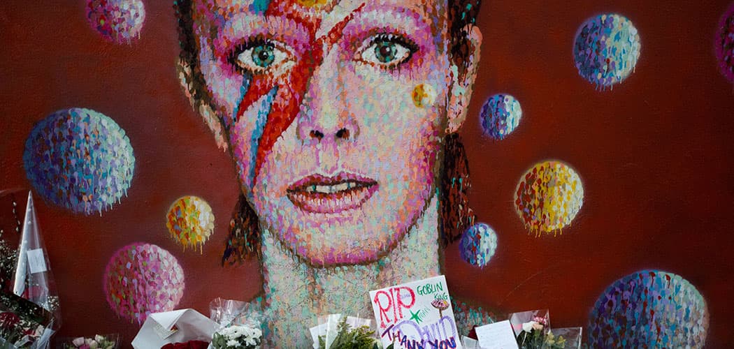 Tributes lie beneath a mural of British singer David Bowie by artist Jimmy C in Brixton, south London on Jan. 12, 2016. (Matt Dunham/AP)