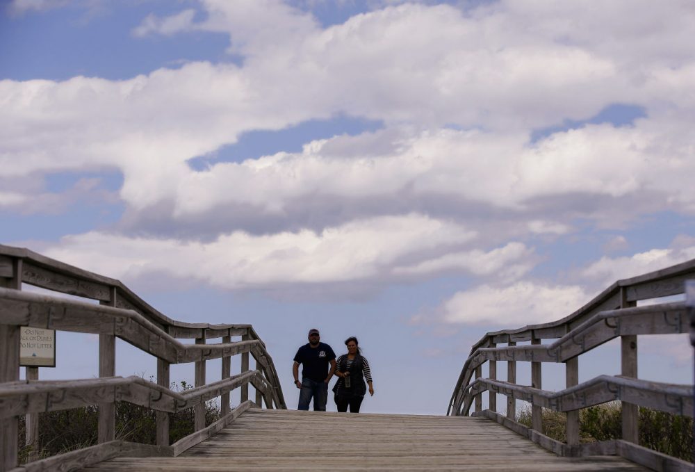 Two people walk across a beach bridge on Duxbury Beach. Duxbury is the first town on the south shore to institute a fine for underage drinking. (AP Photo/Stephan Savoia)