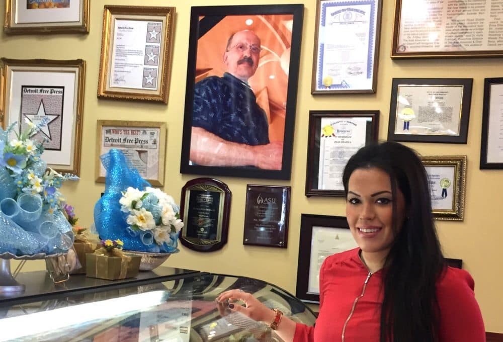Nada Shatila, owner of Shatila Bakery &amp; Cafe in Dearborn, Michigan, stands next to a photo of her father Riad Shatila, a Lebanese immigrant, founded it it 1979. (Robin Young/Here &amp; Now)
