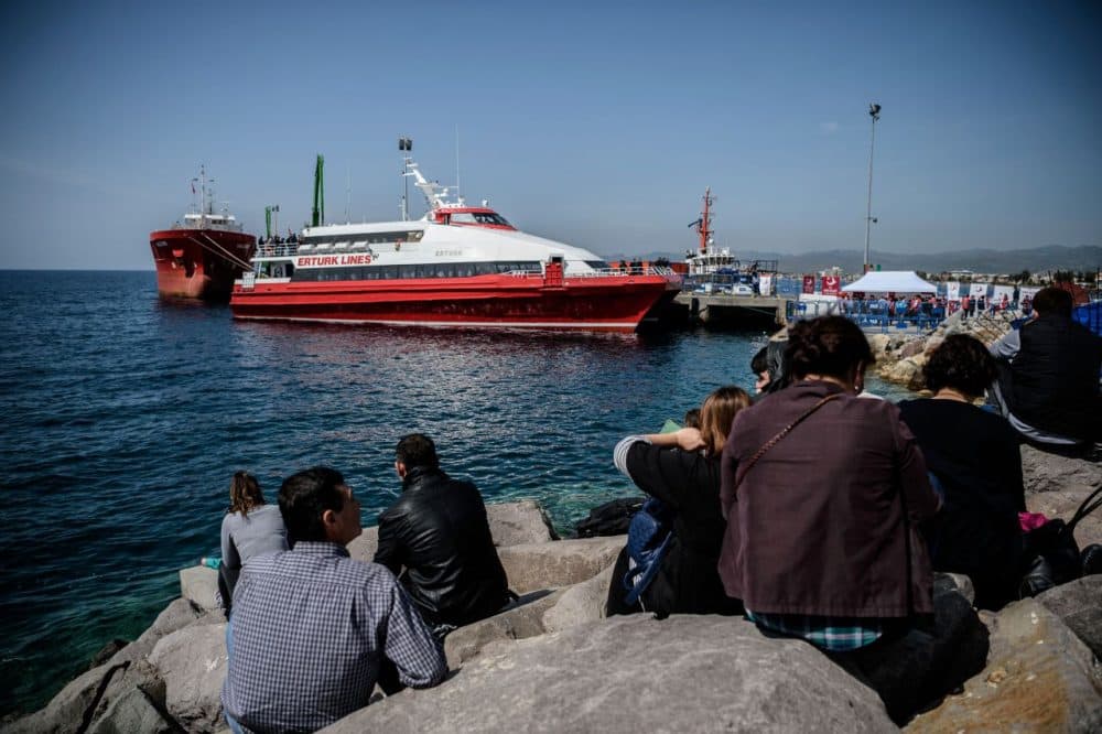 People gather on the beach as migrants deported from Greece arrive aboard a small Turkish ferry as part of an EU deal. (Ozan Kose/AFP/Getty Images)