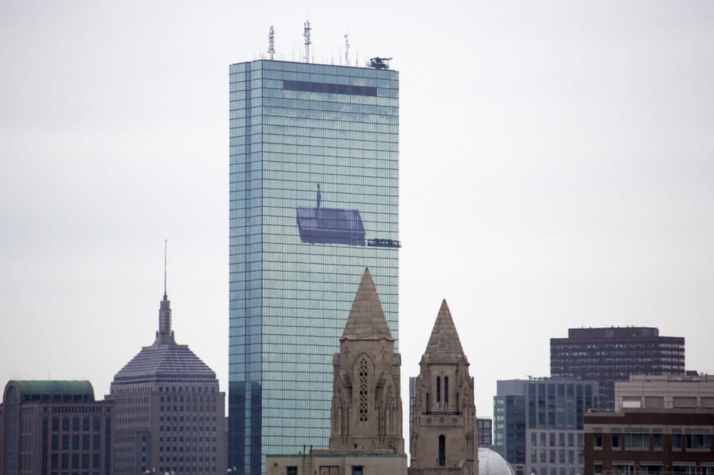 A crew lowers scaffolding ahead on the former John Hancock Building before removing JR's mural. (Jesse Costa/WBUR)