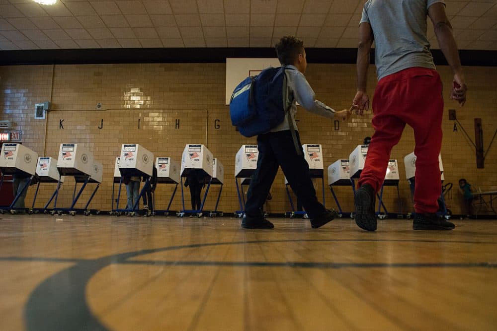 A man with his son walk past voting booths at Public School 22 on April 19, 2016 in the Brooklyn borough of New York City. Voters are going to the polls in New York for the presidential primary election. (Stephanie Keith/Getty Images)