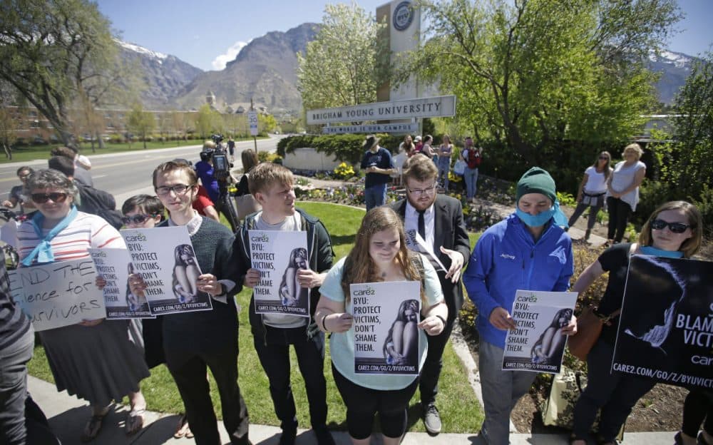Protesters stand in solidarity with rape victims on the campus of Brigham Young University during a sexual assault awareness demonstration Wednesday, April 20, 2016, in Provo, Utah. BYU students who say they were sexually assaulted are finding themselves under investigation for possible violations of the Mormon school's honor code against sex and drinking. BYU says it will re-evaluate the practice. (Rick Bowmer/AP)